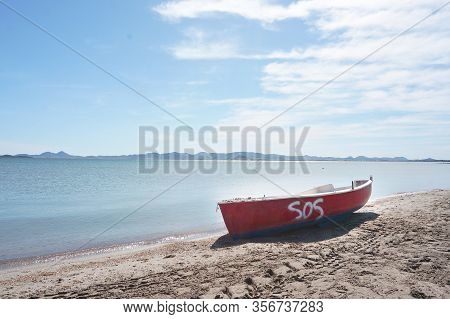 Lonely Red Vessel Boat Lauing On Sandy Beach On Quiet Sunny Day
