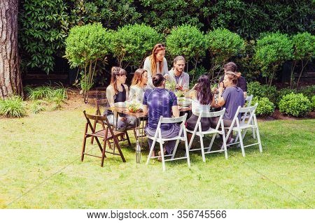 Friends In Sportswear Eating Outdoors. Sporty Young Male And Female Friends Gathering Around Table A
