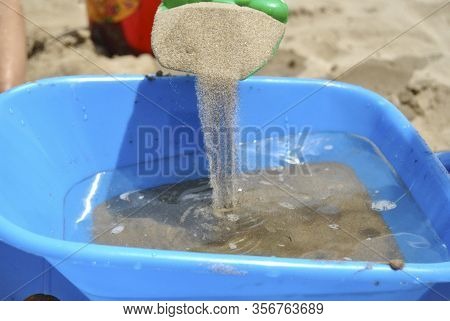 Boy Playing With The Beach Sand In A Trolley