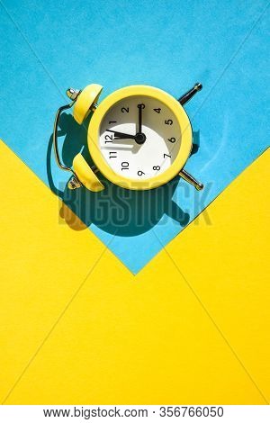 Yellow Vintage Alarm Clock On A Blue And Yellow Background With Selective Focus, Copy Space For Text