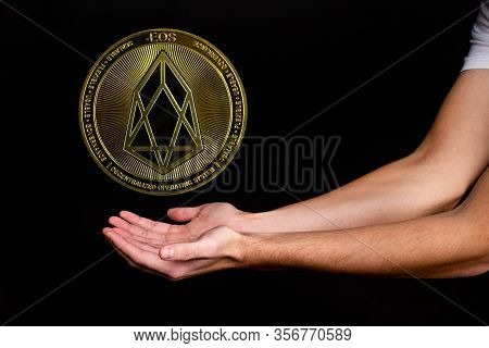 The Symbol Of The New Popular Cryptocurrency Eosio With The Image Of Hands On Dark Background