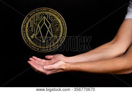 The Symbol Of The New Popular Cryptocurrency Eosio With The Image Of Hands On Dark Background