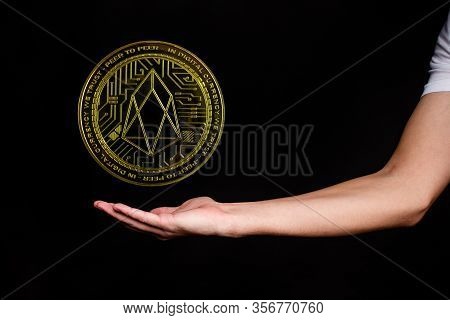 The Symbol Of The New Popular Cryptocurrency Eosio With The Image Of Hands On Dark Background
