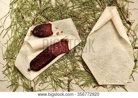Dried Sausage Made Of Roe Meat On Parchment Left And Right With A Rolled-up Empty Paper Scroll On Pi