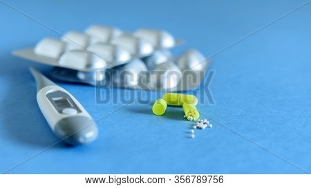 Thermometer And Capsule Tablets On The Blue Background Closeup. Anti Virus, Anti Flu Medicine. Self 