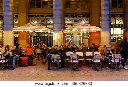 Paris, France - March 12, 2020 : Parisians And Tourists Sit On The Terrace Of Le Nemours Cafe. This 