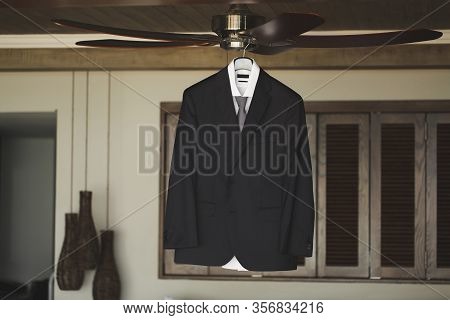 The Grooms Suit Is Hanging On A Hanger.