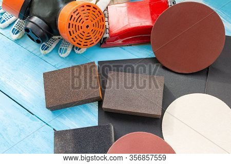 Abrasives, Sansing Paper And Sanding Sponges And Sanding Wheel Respirator On The Blue Wooden Backgro