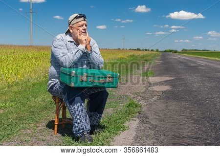 Portrait Of Caucasian Senior Having Short Rest On A Roadside Sitting On A Whicker Stool With An Anci
