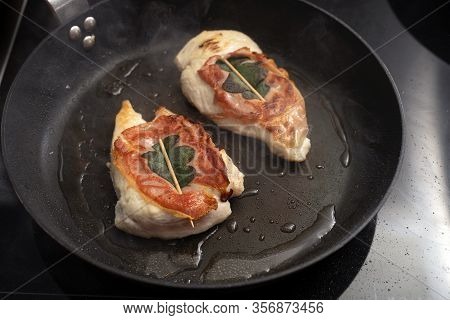 Roasted Chicken Saltimbocca Wrapped With Air-dried Ham And Sage Leaves In A Black Pan On The Stove, 