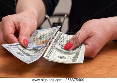 Womans Hands Counting Hundred Dollar Bills Over The Table. Selective Focus