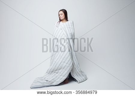 Healthy Sleep And Drowsiness, Beautiful Young Woman Standing Wrapped In A Blanket, Light Gray Backgr