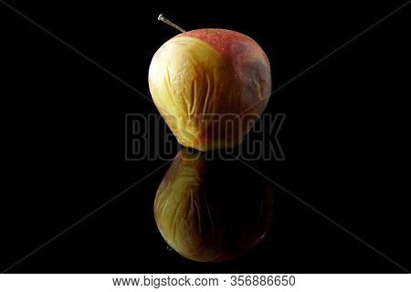 Rotting Apple On Black Background With Reflection