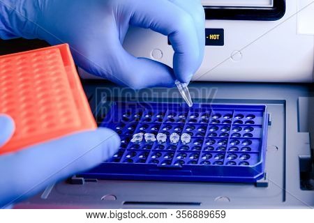 Loading A Dna Tube Into A Pcr (polymerase Chain Reaction) Thermocycler Machine In A Bioscience Labor