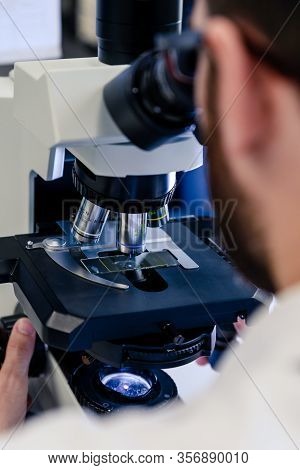 Scientific Handling A Light Microscope Examines A Laboratory Sample For Pharmaceutical Bioscience Re