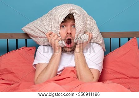 Cauacsian Young Man With Pillow On Head Lying In Bed And Screaming