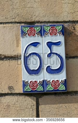 A Close Up View Of The Number Sixty Five Embosed On A Clay Plate For Outside Your Front Door