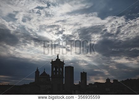 Dramatic sky with dark clouds over Bergamo Upper City towers and church domes. Lombardy regoin of northern Italy became an epicenter of viral pandemic of coronavirus disease 2019 (COVID-19)