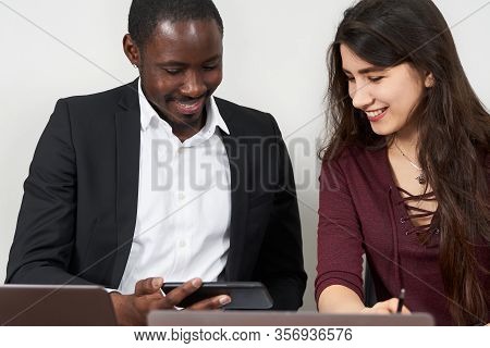 Multiethnic Colleagues Use Cellphones And Try Smartphone Applications In Office