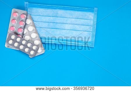 Medical Sick Mask With A Blister Of Pills On A Blue Background Top View, Medicl Theme.