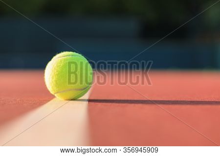 Bright Greenish Yellow Tennis Ball On The Line.