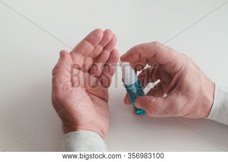 Hand Treatment With An Antiseptic Drug. Mens Hands With A Bottle Of Hand Handling In The Frame. Coro