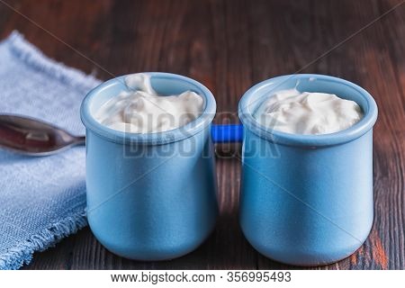 Healthy Organic Fresh And Delicious Creamy Yogurt In Blue Ceramic Cups On White Wooden Tabke.