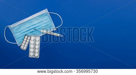 White Medicine Blister Packs Pills, Thermometer, Medical Face Mask Flat Lay On Colorful Blue Backgro