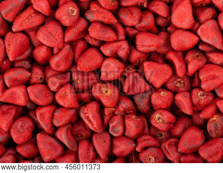 Annatto Seeds Background. Achiote Seeds, Bixa Orellana. Natural Dye For Cooking And Food. Close-up. 