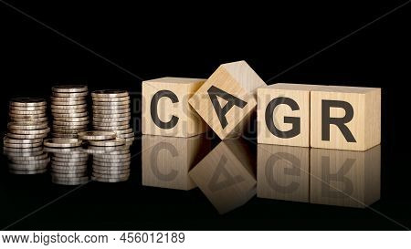 Cagr. Wooden Cubes. Black Background. Stacks With Coins. Inscription On The Cubes Is Reflected From 