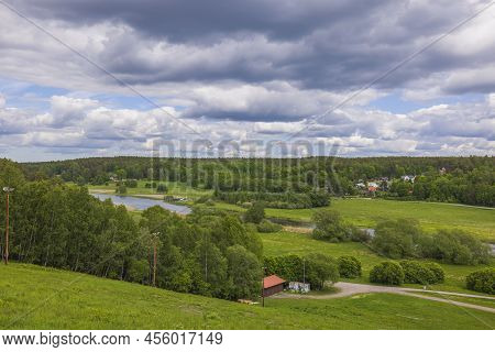 Amazing Green Summer Nature Landscape View. Fiew Buildings On Green Fields Between Green Forest Tree