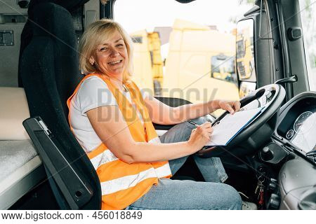 Mature Woman Truck Driver Steering Wheel Inside Lorry Cabin. Happy Middle Age Female Trucker Portrai