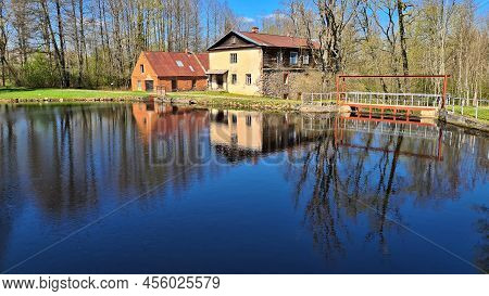 Water Mill On The Shore Of Lake And Its Reflection On The Surface Of The Water In Latvian Village Of