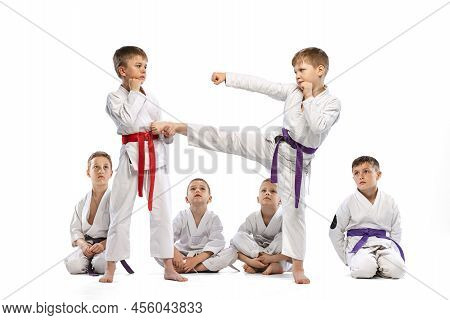 Little Beginner Karate Fighters In White Doboks And Colorful Belts Training Isolated On White Backgr