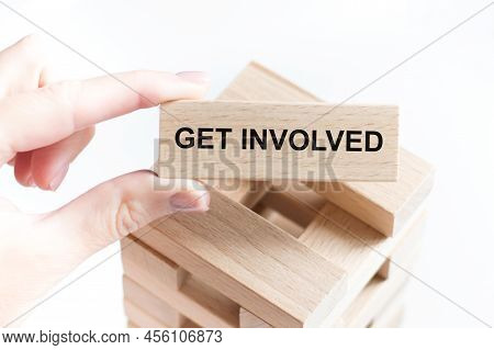Cropped View Of Hands Holding Wooden Cube With Get Involved Lettering On Work Table. Top View