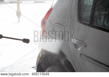A Process Of Flushing Soap Sud On Silver Car With Pressurised Water Stream At Self-service Indoor Ca