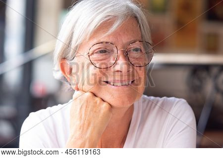 Close Up Portrait Of A Beautiful Senior Caucasian Woman With White Short Hair And Eyeglasses As She 