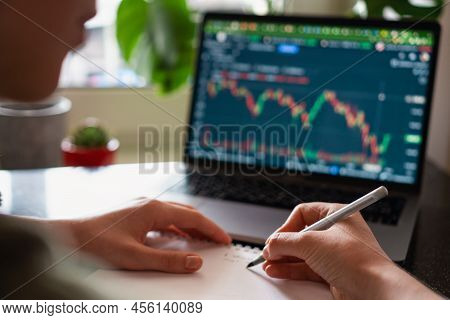 Female Hands Writing Down Numbers From Laptop. Investment Analysis, Trading Concept. Technology, Dig