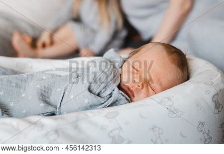 Close Portrait Of Newborn Boy In Cocoon. Happy Caucasian Family Of Four People. Baby Boy Infront Of 