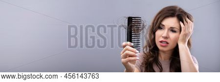 Close-up Of A Worried Woman Holding Comb Suffering From Hairloss