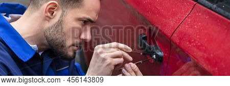 Young Man Opening Red Car Door With Lockpicker