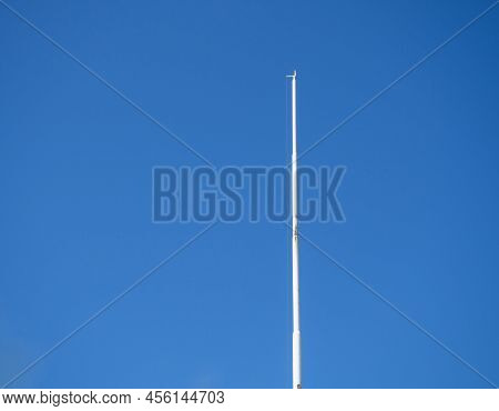 Empty White Flagpole Against The Blue Sky. Lowered Flag. National