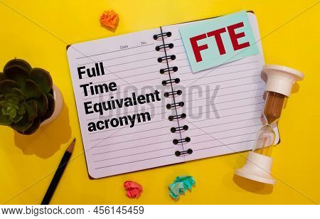 Text Fte Full Time Equivalent Writing On Notebook With Hand Holding Pencil,clock,calculator And Glas