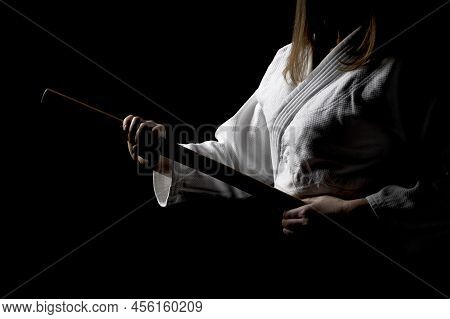 A Girl In Black Hakama Standing In Fighting Pose With Wooden Sword Bokken Over Dark Background. Shal