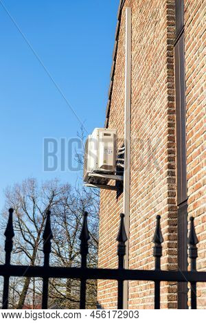 Brecht,belgium - March 4 2022: An Air Conditioning Unit Hanging Outside Of A Building On A Brick Wal