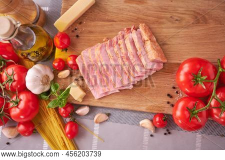 Sliced Pancetta Ham Bacon On Wooden Cutting Board At Domestic Kitchen