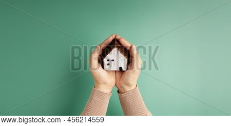 House And Family Insurance Concepts. Hand Holding A Wooden Toy House With Love And Gentle Care. Cust
