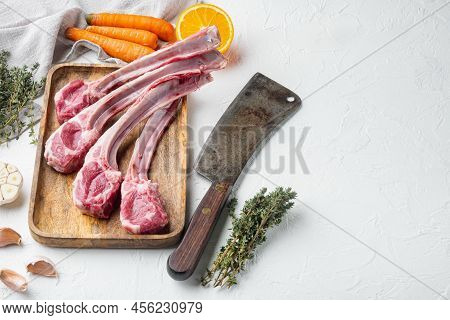 Raw Lamb Filets On Bone Set, With Ingredients Carrot Orange, Herbs, And Old Butcher Cleaver Knife, O