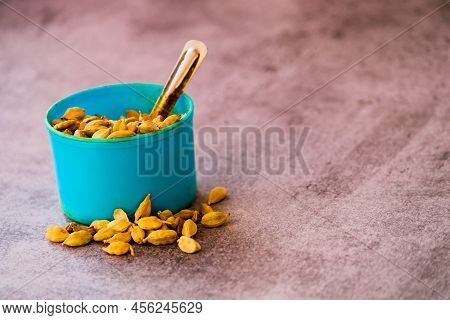 Dry Green Cardamom Seeds On Black Background With Blue Cup With Selective Focus,