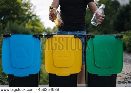 Close Up Of Man Hold Two Different Bottle, Plastic And Glass And Thowing Into Different Recycling Bi